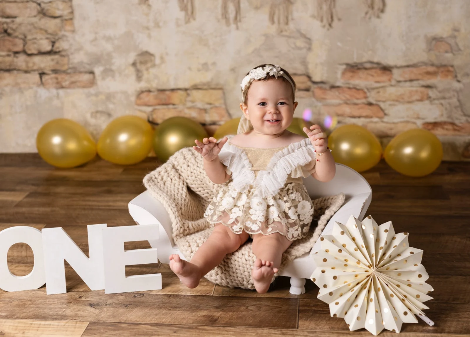 Una bambina festeggia il primo compleanno tra palloncini dorati e lettere ONE