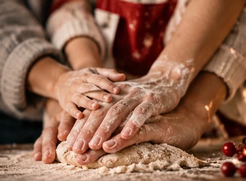 Mani di famiglia che impastano insieme i biscotti di Natale